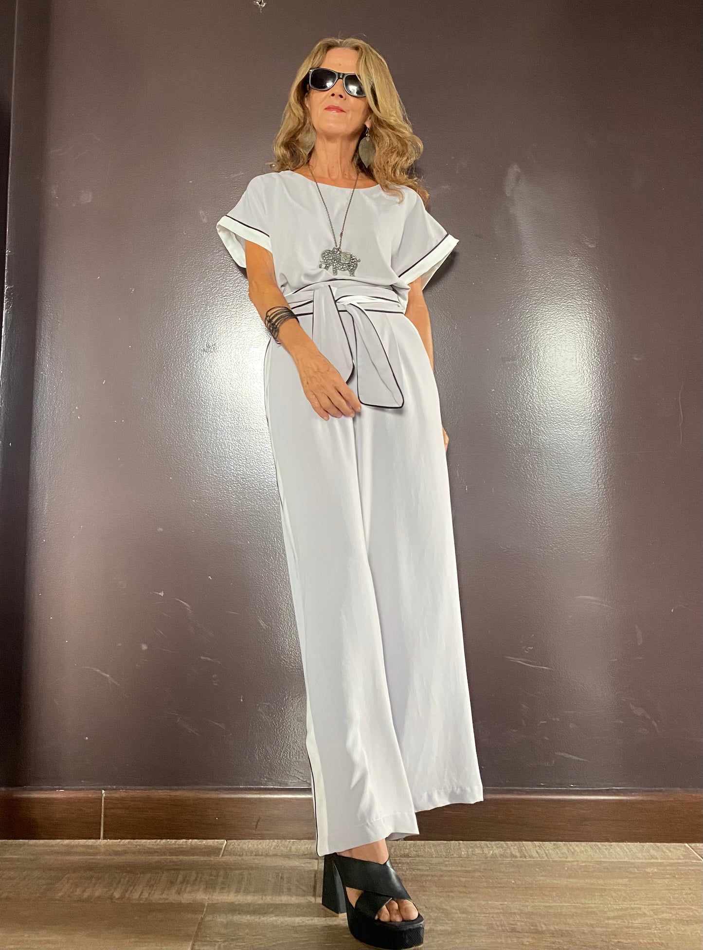 Mujer usando enterizo elegante con cinturón y franjas laterales, ideal para eventos, trabajo o salidas casuales