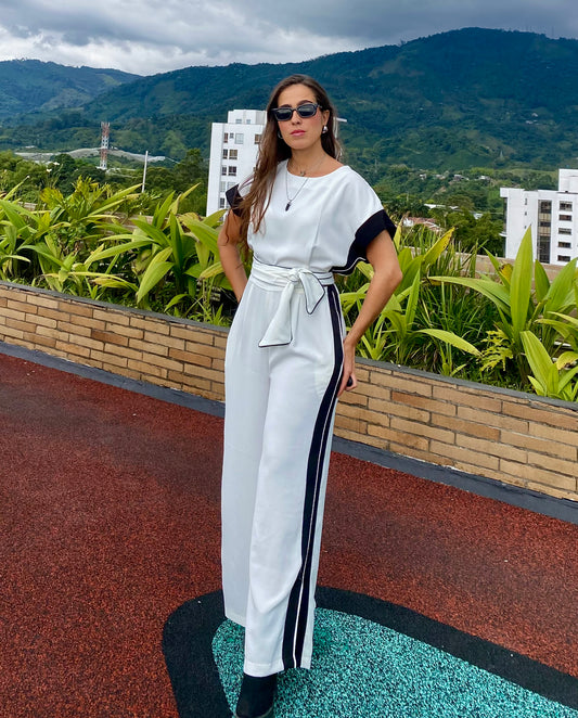 Mujer usando enterizo elegante con cinturón y franjas laterales, ideal para eventos, trabajo o salidas casuales