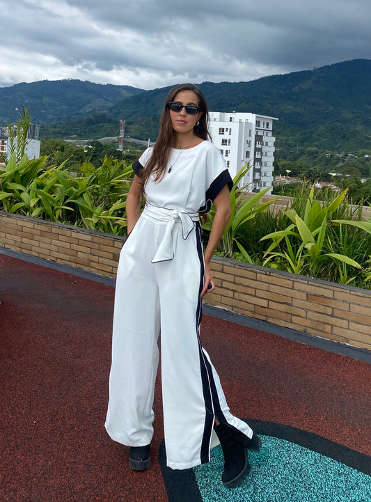 Mujer usando enterizo elegante con cinturón y franjas laterales, ideal para eventos, trabajo o salidas casuales